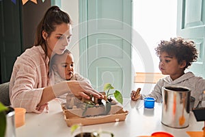 Friendly mother spending time with her kids while sitting at the kitchen at the table