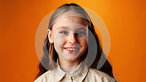 Friendly nice teen girl smiling against yellow background in studio