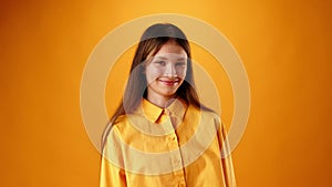 Friendly nice teen girl smiling against yellow background in studio
