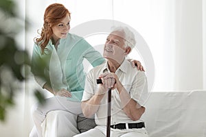 Friendly nurse and smiling elderly man with walking stick in the