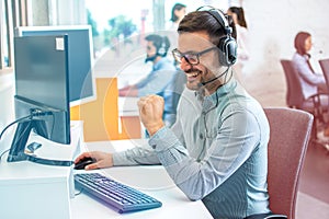 Friendly operator with hands-free headset talking with client during online phone call giving adequate answers to client