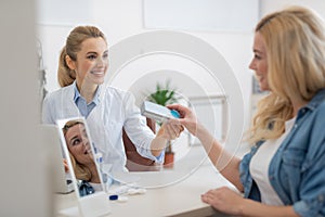 Friendly ophthalmologist in white lab coat prescribing contact lenses for blond lady