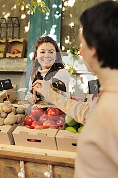 Friendly organic fruits and veggies shop owner offering clients to taste