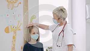 Friendly paediatrician measuring little girl`s height at a consult