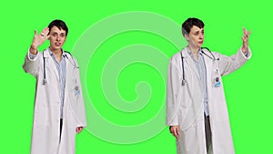 Friendly physician inviting people to come closer to her against greenscreen