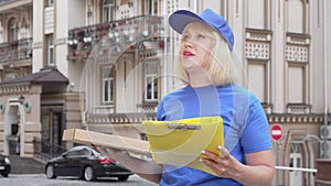 Friendly pizza delivery woman smiling to the camera while working in the city