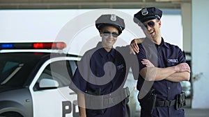 Friendly police officers in uniform and glasses smiling to camera, law and order