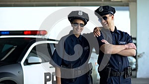 Friendly police officers in uniform and glasses smiling to camera, law and order