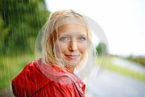 Friendly, portrait and young woman in the rain with coat in nature, road or street for winter. Smile, positive attitude