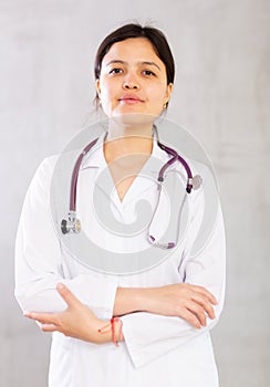Friendly professional female doctor in white coat with phonendoscope