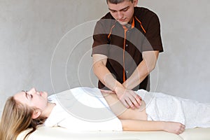 Strong male masseur with gentle hand movements kneads belly of c