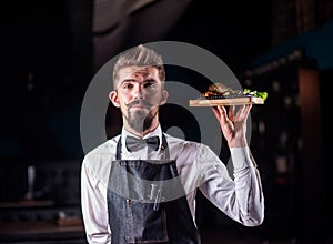 Friendly restaurant employee serves appetizing dish on a black background.