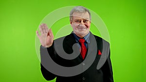 Friendly senior businessman waves palm for greeting or goodbye sign.