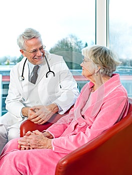 Friendly senior male doctor chatting to a patient.