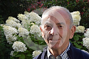 Friendly senior man posing for a portrait in his garden