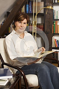 Friendly senior woman sitting and reading a book