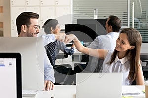 Friendly smiling colleagues fist bumping at workplace photo