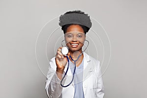 Friendly smiling confident female healthcare professional. Doctor woman in labcoat holding stethoscope on white background
