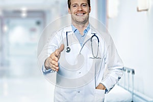 Friendly smiling doctor in hospital hallway ready for handshake