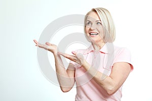 Friendly smiling middle aged woman pointing at copyspace isolated