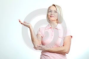 Friendly smiling middle aged woman pointing at copyspace isolated