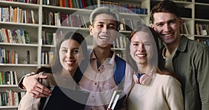 Friendly smiling schoolmates pose for camera in library