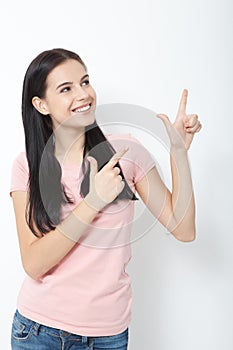 Friendly smiling woman pointing at copyspace isolated on white background