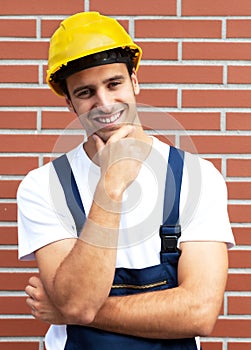 Friendly smiling worker in front of a brick wall