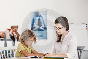 Friendly teacher doing homework with young boy