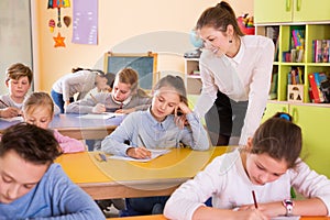 Teacher woman helping children during lesson in schoolroom photo