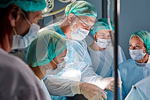 Friendly team of caucasian surgeons in operating room with surgery equipment