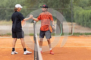 Friendly tennis match - opponents shake hands above the net