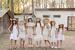 Friendly tween girls standing on courtyard of country house in pine forest in summer