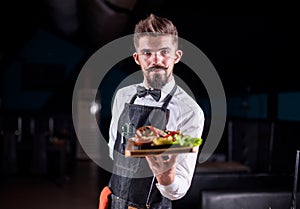 Friendly waiter helpfully holds cooked dish in the restaurant.