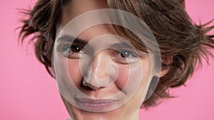 Friendly white woman smiling, kind happy girl portrait on pink studio. Wavy hairstyle, natural makeup