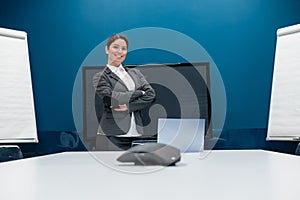 Friendly woman dressed in a suit conducts an online conversation on a laptop in a conference room. Female business coach