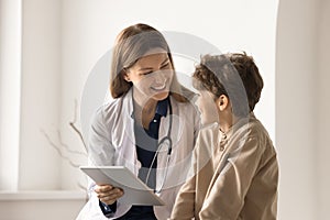 Friendly woman paediatrician using tablet consulting to child patient