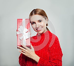 Friendly woman showing gift box and smiling on white background