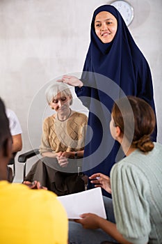 Friendly young Asian woman talking to classmates sitting in circle