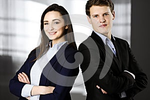 Friendly young colleagues are standing as a team with crossed arms in a modern office. Portrait of successful business