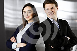 Friendly young colleagues are standing as a team with crossed arms in a modern office. Portrait of successful business