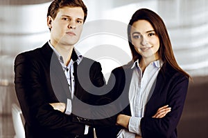 Friendly young colleagues are standing as a team with crossed arms in a modern office. Portrait of successful business