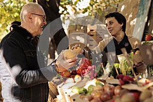 Friendly young farmer selling organic vegetables from farming stand