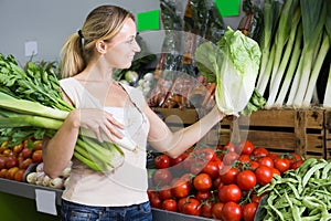 friendly young female customer holding fresh celery and leek