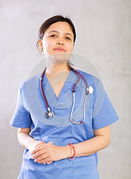 Friendly young female doctor in blue scrub with phonendoscope