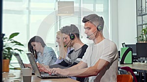 Friendly young man smiling to the camera, working at customer support call center