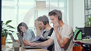 Friendly young man smiling to the camera, working at customer support call center