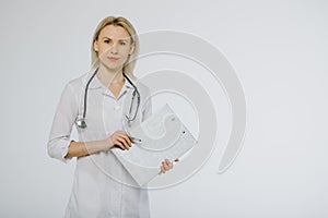 Friendly young nurse holding a clipboard - medical record and a pen isolated over a white background.