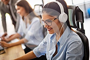 Friendly young woman helpline operator with headphones in call center