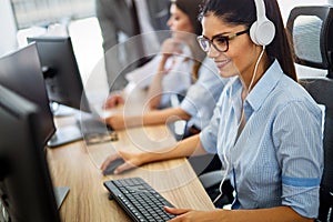 Friendly young woman helpline operator with headphones in call center